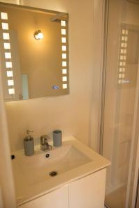 een witte badkamer met een wastafel en een spiegel bij Petite Maison située entre Saint-Malo et Cancale in Saint-Méloir-des-Ondes
