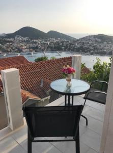 una mesa con un jarrón de flores en el balcón en Sunset Rooms Dubrovnik, en Dubrovnik