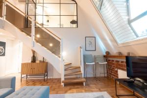een woonkamer met een trap in een loft bij 2ndhomes Luminous & Modern 107m2 Penthouse in Kruununhaka in Helsinki