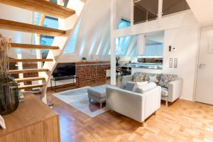 ein Wohnzimmer mit einer Treppe, einem Sofa und Stühlen in der Unterkunft 2ndhomes Luminous & Modern 107m2 Penthouse in Kruununhaka in Helsinki