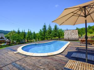 a large swimming pool with an umbrella and chairs at Gościniec Rabe - Agro&SPA in Ustrzyki Dolne