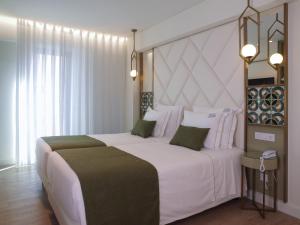 een slaapkamer met een groot wit bed met een groot hoofdeinde bij New Style Lisbon Hotel in Lissabon +39 foto's