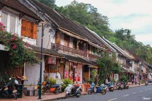 a street with motorcycles parked in front of buildings at Luang Prabang Rosie Place in Luang Prabang