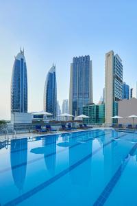 a swimming pool with a city skyline in the background at Rose Rayhaan by Rotana - Dubai in Dubai