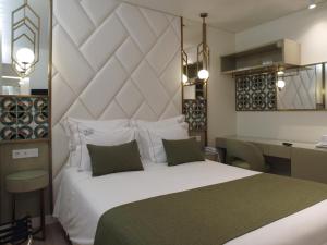 a bedroom with a large white bed and a desk at New Style Lisbon Hotel in Lisbon
