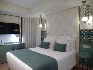 a bedroom with a large white bed and a television at New Style Lisbon Hotel in Lisbon