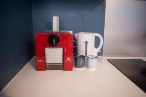 een rood koffiezetapparaat en kopjes op een aanrecht bij T2 Cosy & moderne avec Parking Privé Gratuit à Villeurbanne in Villeurbanne