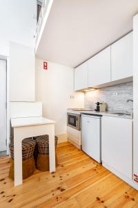 a kitchen with white cabinets and a wooden floor at VIVA Library Studio in Porto