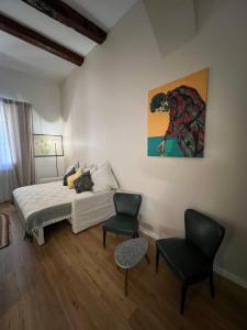 a bedroom with a bed and two chairs and a painting at HouSmart Senzanome 9/3 in Bologna