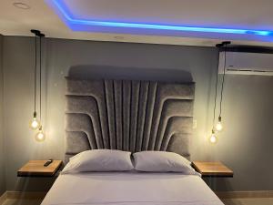 Un dormitorio con una cama con una luz azul encima. en Soho Deluxe en Medellín