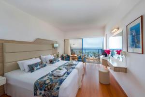 a bedroom with a large bed with a view of the ocean at Ascos Coral Beach Hotel in Coral Bay