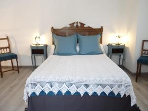 a bedroom with a bed with blue pillows and two chairs at La Bouillarde in Suze