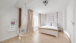a white bedroom with a bed and a chair at Apartamenty Sun & Snow Ustka Centrum in Ustka