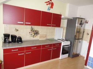 Il comprend une cuisine équipée de placards rouges et d'un réfrigérateur blanc. dans l'établissement Sehr-schoene-4-Raum-Maisonette-Fewo-mit-110qm-Balkon-zentral-preiswert-T7, à Dresde
