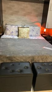 1 cama grande con 2 reposapiés y 2 bancos en Flat de luxo São Paulo - Guarulhos en Guarulhos