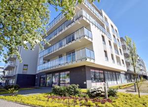 duży biały budynek z wieloma oknami w obiekcie Apartament Kapitalny przy porcie w Kołobrzegu z rowerownią i placem zabaw w Kołobrzegu