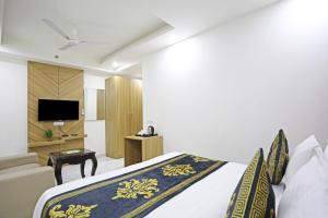 ニューデリーにあるHotel Decent Suites - Delhi Airportのベッドとテレビが備わるホテルルームです。