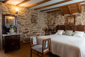 a bedroom with a bed and a stone wall at Os Migueliños in Catoira