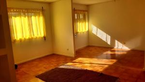 ein leeres Wohnzimmer mit gelben Vorhängen und einem Teppich in der Unterkunft taol in Vila Nova de Gaia