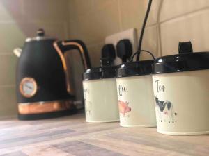 three coffee pots sitting on a counter next to a tea kettle at Cosy Homely Apartment close to Lincoln City Centre in Lincoln