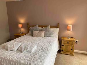 a bedroom with a white bed with two lamps on tables at Cosy Homely Apartment close to Lincoln City Centre in Lincoln