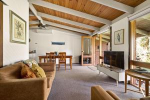 sala de estar con sofá y TV en Kiewa Country Cottages, en Mount Beauty