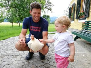 Ein Mann mit einem Huhn und einem kleinen Mädchen in der Unterkunft Weslhof in Attersee am Attersee