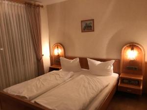 a bedroom with a bed with white sheets and two lamps at Linde Diersburg Stammhaus in Diersburg