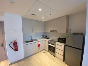 uma cozinha com armários brancos e um frigorífico preto e branco em Home-like modern 1 bedroom apartment SeaWorld view em Abu Dhabi