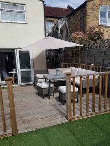 una terraza de madera con mesa y sombrilla en Beautiful home in London, en Londres