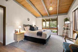 1 dormitorio con cama y techo de madera en Kiewa Country Cottages en Mount Beauty