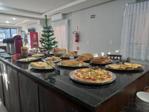 a buffet with many different types of pizzas and a christmas tree at Sognare Hotel in Caçador