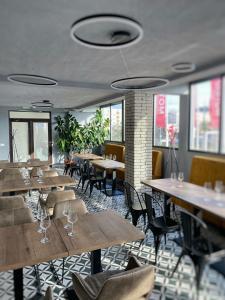 um restaurante com mesas e cadeiras de madeira e janelas em Dr House em Mioveni