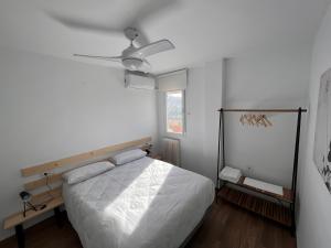 a white bedroom with a bed and a ceiling fan at Apartamento en Granada in Granada