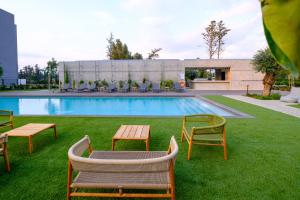een zwembad met stoelen en een tafel in het gras bij Sunset Gardens in Limassol