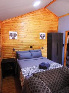 - une chambre avec un lit et un mur en bois dans l'établissement ZUCH Accommodation at Pafuri Self Catering - Guest Cabin, à Polokwane