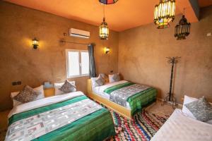1 dormitorio con 2 camas y lámpara. en Kasbah Du Berger & Piscine en Merzouga
