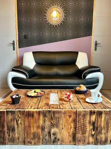 un sofá de cuero negro sentado detrás de una mesa de café de madera en * La Maisonette * avec Sauna & Hammam privatifs, en Nevers