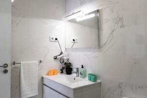 La salle de bains blanche est pourvue d'un lavabo et d'un miroir. dans l'établissement Almada Downtown 103, à Porto