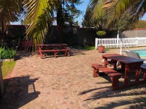 stół piknikowy i ławki na ceglanym patio w obiekcie Sibahlenomhlambi Guesthouse w mieście Springs