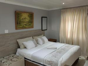Un dormitorio con una gran cama blanca y una ventana en Sibahlenomhlambi Guesthouse en Springs