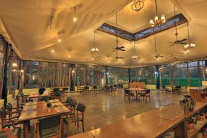 a restaurant with tables and chairs and windows at Bison Retreat - Pench 