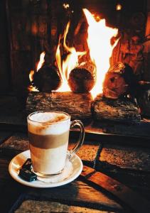 a cup of coffee sitting on a table in front of a fireplace at Wildberry cottage in Orgères-la-Roche