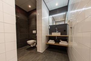 een badkamer met een toilet, een wastafel en een spiegel bij Hotel Parkzicht Eindhoven in Eindhoven