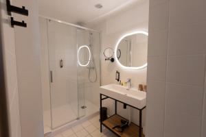 a white bathroom with a sink and a shower at Logis Hôtel & Restaurant Le Vert Bocage in Franqueville-Saint-Pierre
