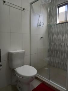 a bathroom with a toilet and a glass shower at Sognare Hotel in Caçador