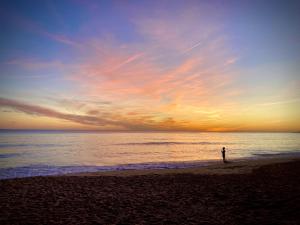 アルブフェイラにあるRegenbogen Properties - Salgados Vila das Lagoasの夕日の浜辺に立つ者