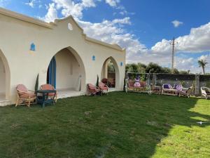 un pequeño edificio blanco con sillas y patio en Lake House by Tunisia Green Resort, en Qaryat at Ta‘mīr as Siyāḩīyah