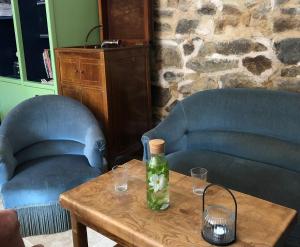 a bottle on a wooden table with two chairs at Fleurs de lin in Saint-Brieuc-des-Iffs