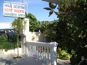 a white fence with a sign in front of a yard at Haus Despina in Sarti